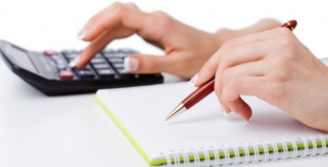 foto das mãos de uma pessoa usando um bloco de anotações e uma calculadora para representar como quitar o empréstimo pessoal