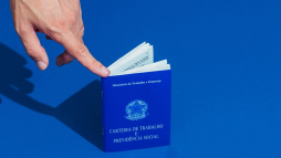 dedo indicador apontando para uma carteira de trabalho simulando a dúvida: 1 ano de carteira assinada tem direito a férias?