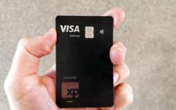 uma mão segurando o cartão XP Visa Infinite