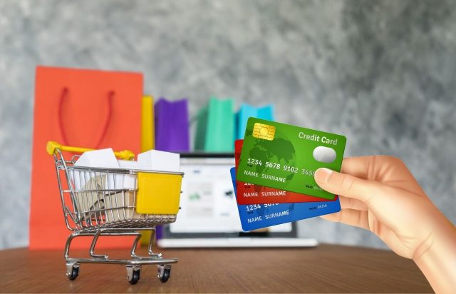 lojas que emitem cartão de crédito na hora - um carrinho de compras e uma mão segurando cartões de crédito