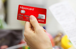 uma mão segurando o cartão de crédito Hipercard da bandeira Hipercard
