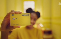 uma mulher segurando o cartão de crédito BB Ourocard Internacional