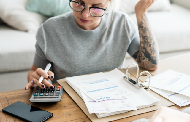 uma mulher usando calculadora para parcelar a fatura do cartão de crédito