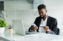 Homem empresário utilizando um cartão de crédito para autônomo on-line ao fazer pedidos via internet móvel, fazendo transações usando o aplicativo do banco móvel