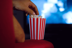 uma pessoa pegando pipoca no cinema assistindo filmes sobre finanças