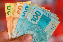 mão segurando notas de 100 reais que ganhou fazenda renda extra