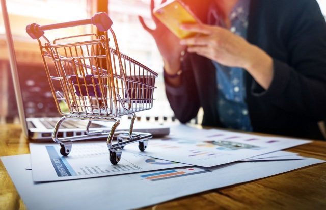 uma mulher fazendo compras pela internet através do celular com um cartão de crédito pré pago virtual