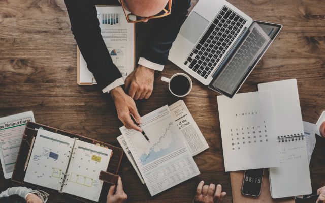 homem que trabalha em corretora com corretagem zero mostrando gráficos de investimento para clientes