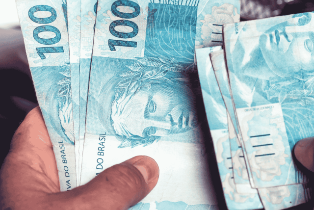 mão segurando notas de dinheiro para representar como ganhar dinheiro extra