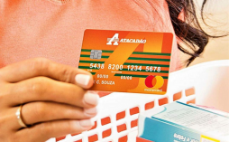 uma mulher segurando o cartão de crédito Atacadão