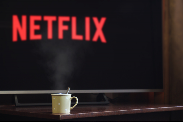 tv ligada com xícara em frente para representar como ganhar dinheiro assistindo Netflix