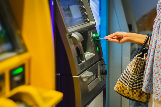 Mulher usando um cartão de crédito para fazer um saque me um caixa eletrônico