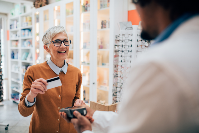 Uma mulher pagando suas compras em uma ótica usando o cartão de crédito para exemplificar o seguro proteção de compra