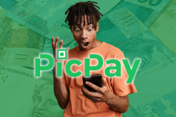 Jovem do sexo masculino com olhar surpreso diante de um celular e notas de dinheiro ao fundo para representar o empréstimo PicPay
