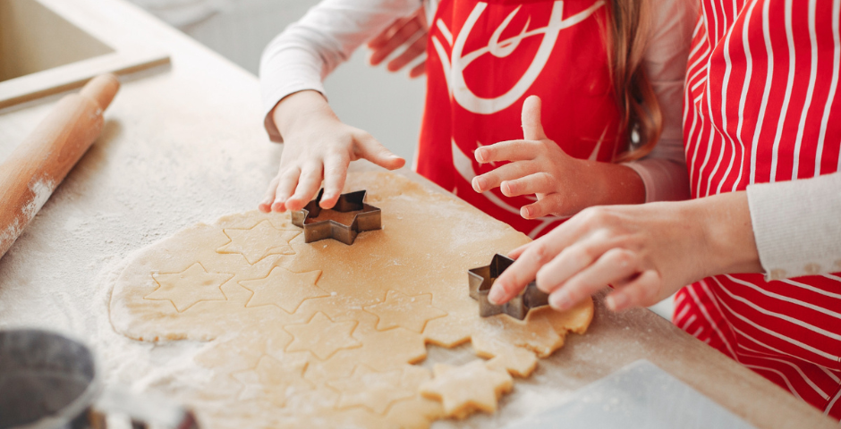 uma mulher e uma criança fazendo biscoitos em forma de estrelas