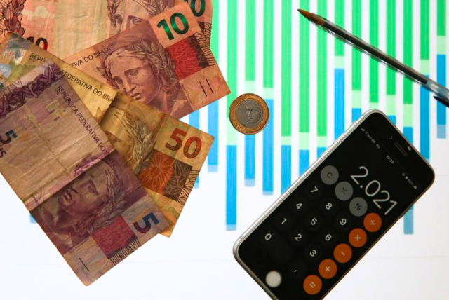 notas de dinheiro e um celular na calculadora - contexto de organização de contas