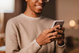 homem sorridente usando smartphone - empréstimo na conta de celular