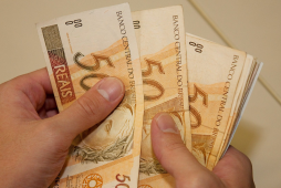 Mão segurando notas de 50 reais, dinheiro de empréstimo