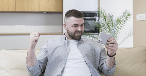 homem segurando um celular e comemorando- Big Time paga mesmo? Descubra se o app é confiável e seguro