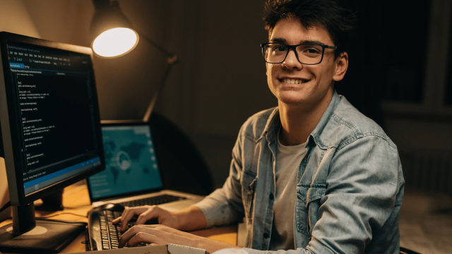 homem olhando para a câmera e sorrindo, ao mesmo tempo em que mexe no computador- GetNinjas é uma boa escolha para freelancers