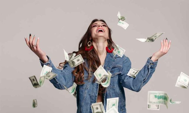 mulher com notas de dinheiro voando ao redor para simbolizar os Dez Pensamentos Que Te Impedem de Ficar Rico