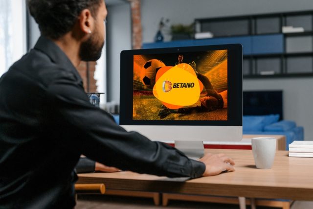 homem sentado em frente ao computador visualizando uma imagem escrita "betano"- Jogo de aposta para ganhar dinheiro: qual é o melhor?