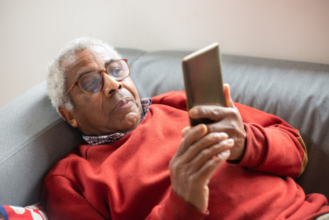 um senhor deitado usando o celular para cancelar empréstimo consignado