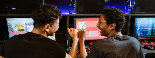 dois amigos se cumprimentando em frente um computador porque sabem ganhar dinheiro jogando