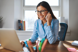 uma mulher em frente ao computador e usando celular aprendendo sobre erros financeiros