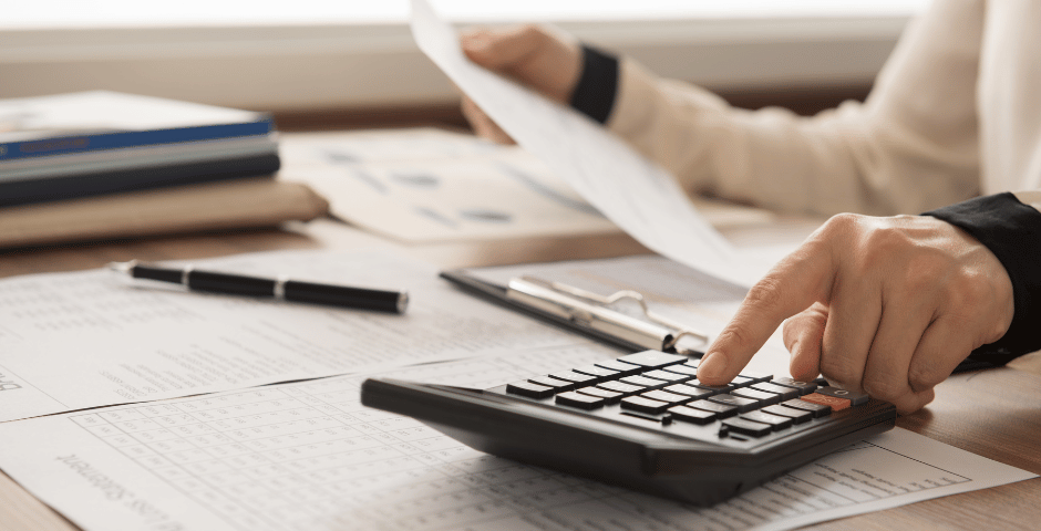 uma pessoa usando uma calculadora e segurando uma folha