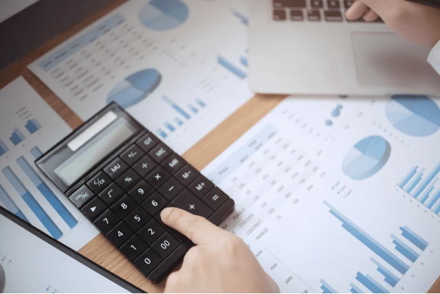 uma pessoa usando uma calculadora para calcular taxas bancárias