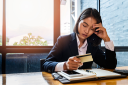 uma mulher segurando um cartão de crédito refletindo sobre os tipos de dívidas