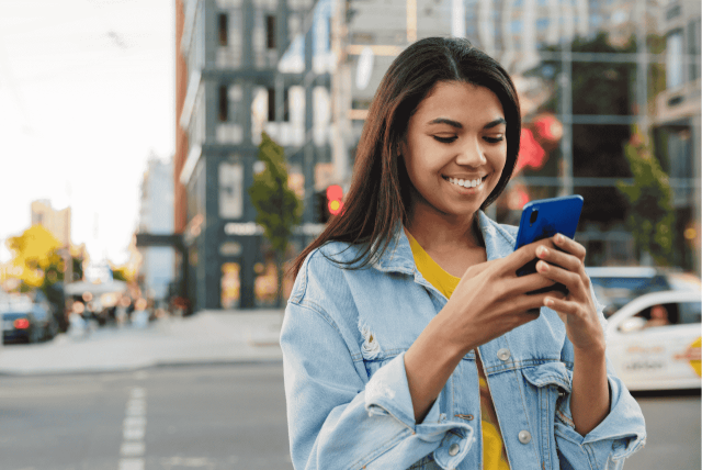 uma mulher usando o celular para representar Como depositar dinheiro no Nubank