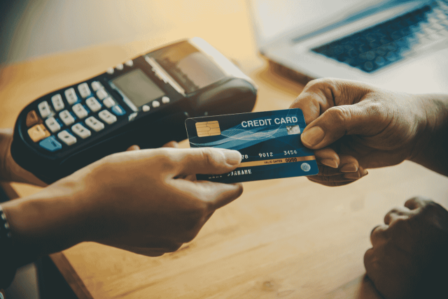 uma pessoa segurando um cartão prestes a fazer uma compra para representar o que é cartão de crédito