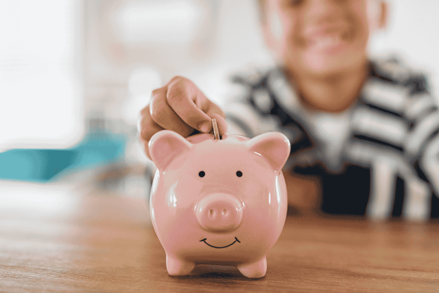 uma criança depositando moeda em um porquinho simbolizando conta poupança para criança