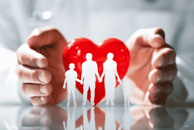 silhueta de uma família entre duas mãos com um coração ao fundo para simbolizar o Seguro de Vida no cartão de crédito