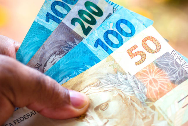 mão segurando notas de dinheiro - novas regras crédito consignado