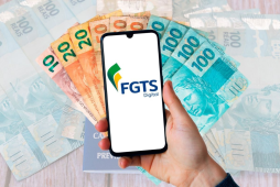 Celular com tela ligada no aplicativo do FGTS em cima de algumas notas de real - fgts preso