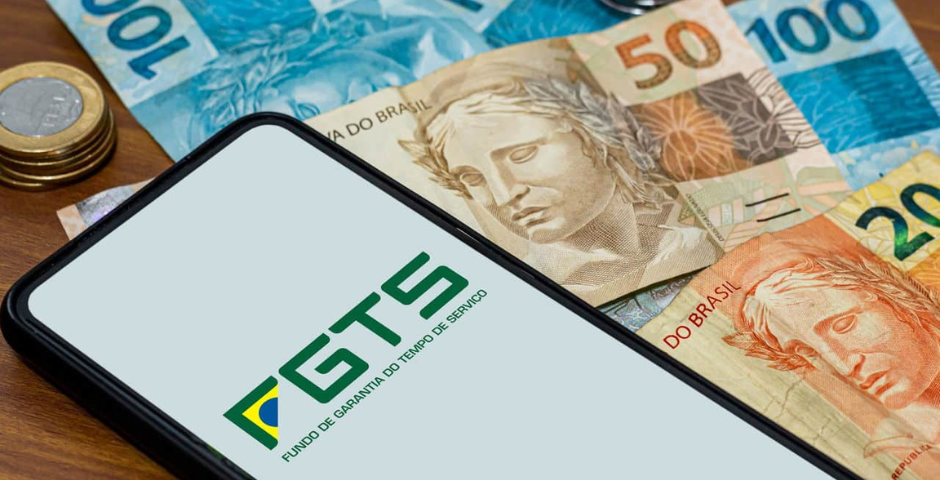Celular com tela ligada no aplicativo do FGTS em cima de algumas notas de real - fgts preso