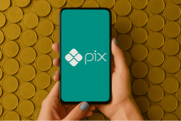 mão segurando celular com logo do pix na tela para representar ganhar pix de graça