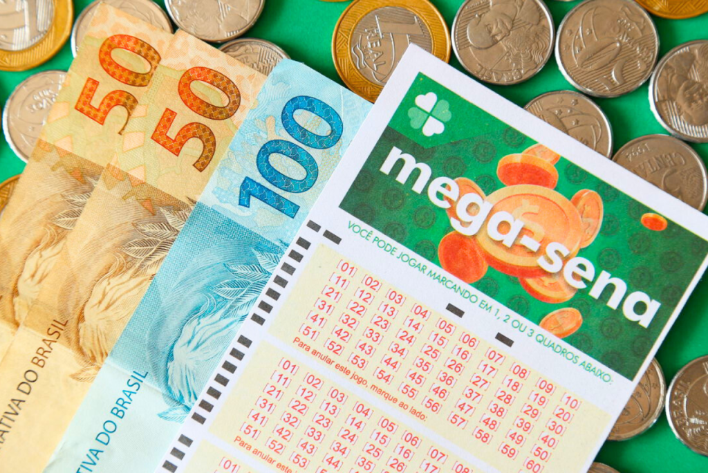 bilhete da mega sena com notas de real ao fundo - Se acertar 2 números na mega sena ganha alguma coisa