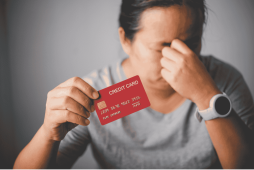 mulher segurando cartão de crédito com expressão de preocupada por pagar fatura do cartão atrasada