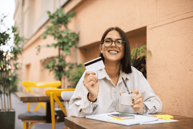 mulher feliz segurando um cartão para representar como rastrear cartão pelo CPF
