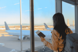 mulher na janela do aeroporto representando as milhas qualificáveis
