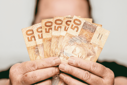 pessoa segurando dinheiro para representar o que é preciso para pedir um empréstimo no banco