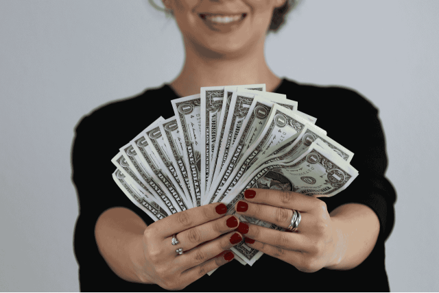 mulher segurando dinheiro de site que paga em dólar