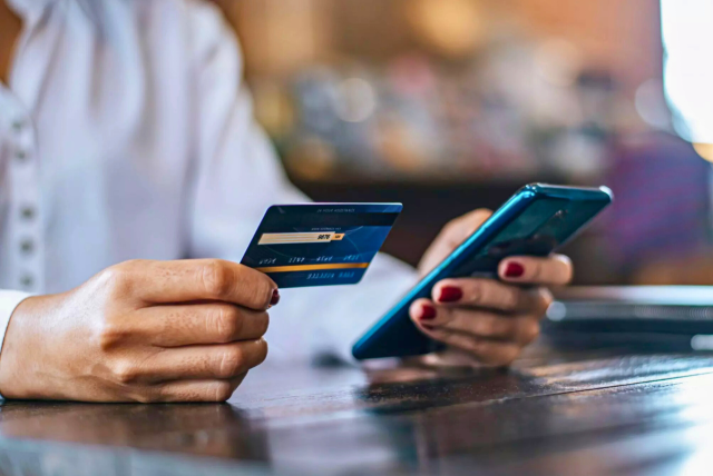 mulher mexendo no aplicativo do banco para cancelar débito automático cartão