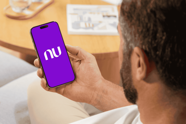 homem olhando para um celular com o logo do Código do Banco Nubank