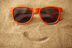 óculos de sol na areia para representar como funciona o pagamento das férias