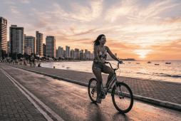 Pôr do sol na Avenida Beira-Mar com mulher pedalando, ideal para economizar em Fortaleza.